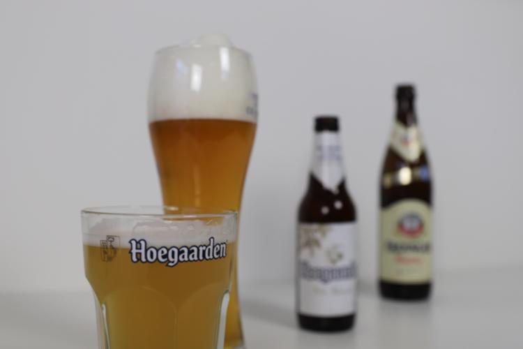 Witbier van Hoegaarden en Weizen van Erdinger Witbier van Hoegaarden en Weizen van Erdinger in glazen met flesjes op de achtergrond