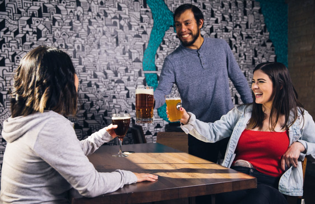 Drie mensen proosten in een bar met bier / Pexels Drie mensen proosten in een bar met bier