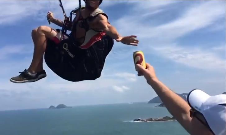 Man vangt een biertje tijdens het paragliden