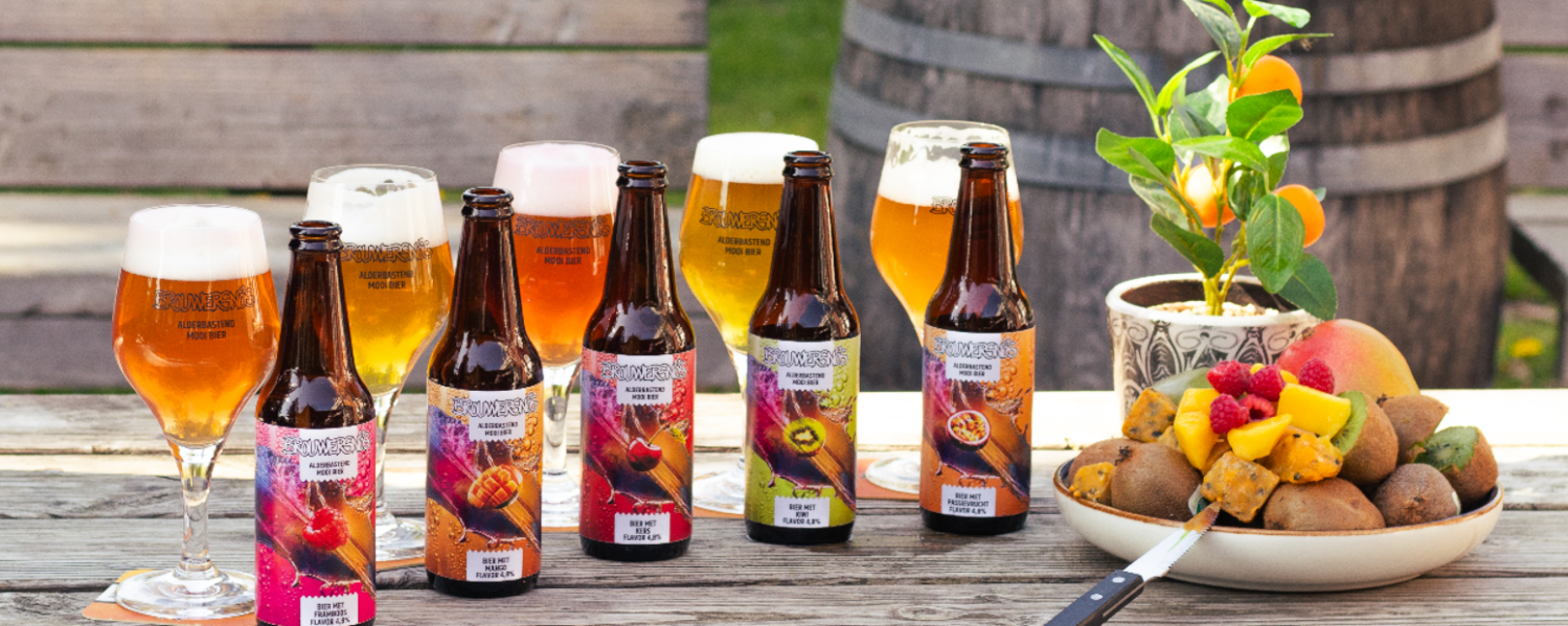 Verschillende zomerse bieren op een houten tafel met vers fruit en een citrusplant.