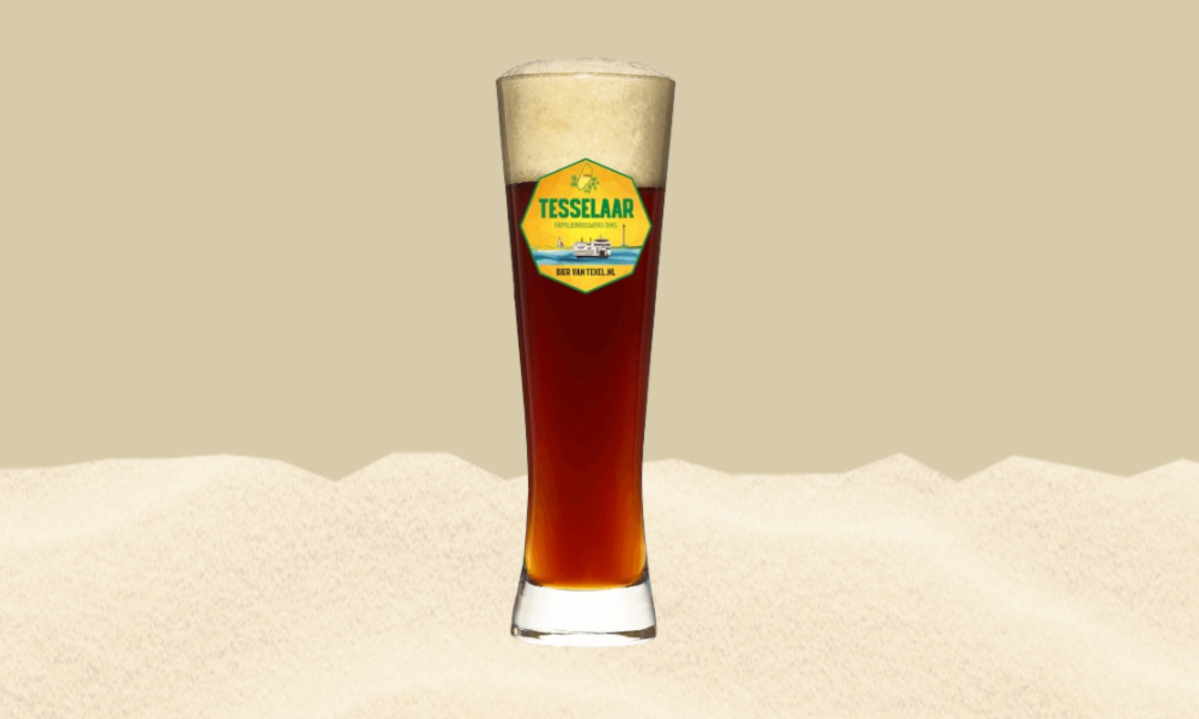 Glas donker bier met schuim op een zandkleurige achtergrond.