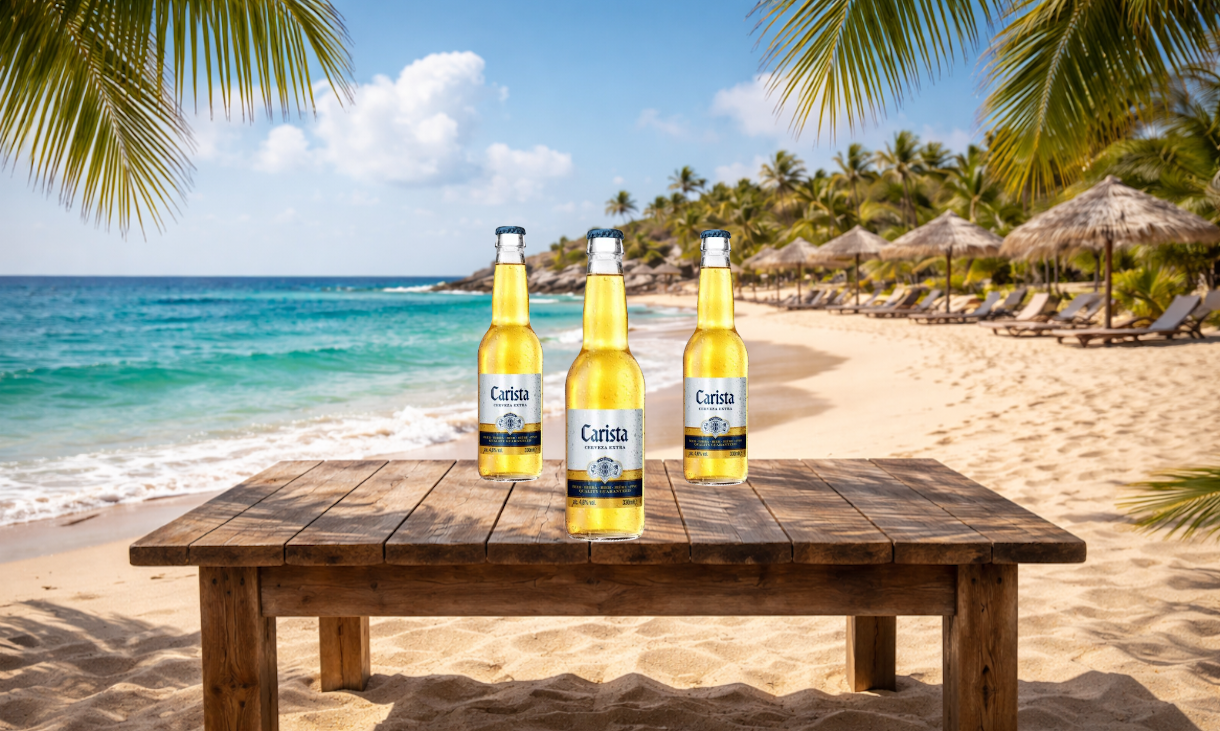Drie flesjes Carista bier op een houten tafel op een tropisch strand met zeezicht.