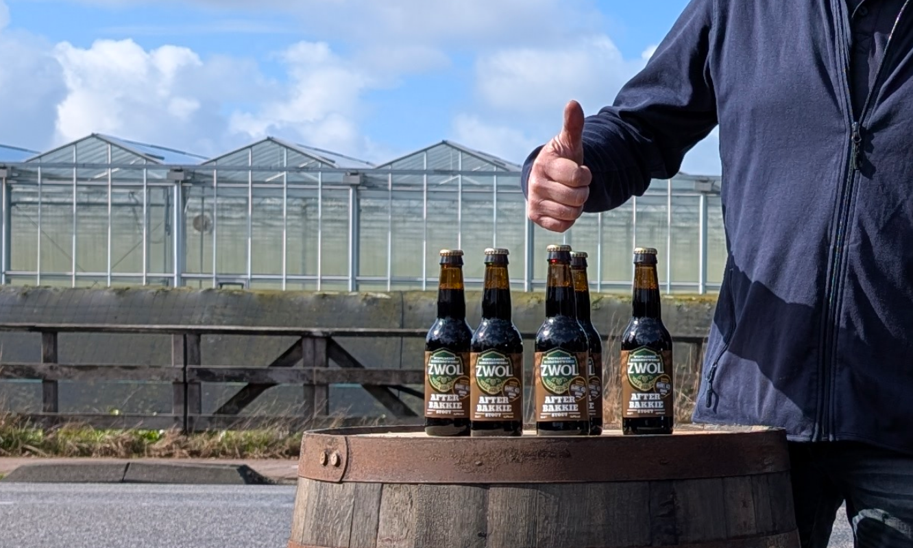 Vijf flesjes ZWOL Afterbakkie bieren op een houten vat met een duim omhoog op de achtergrond.