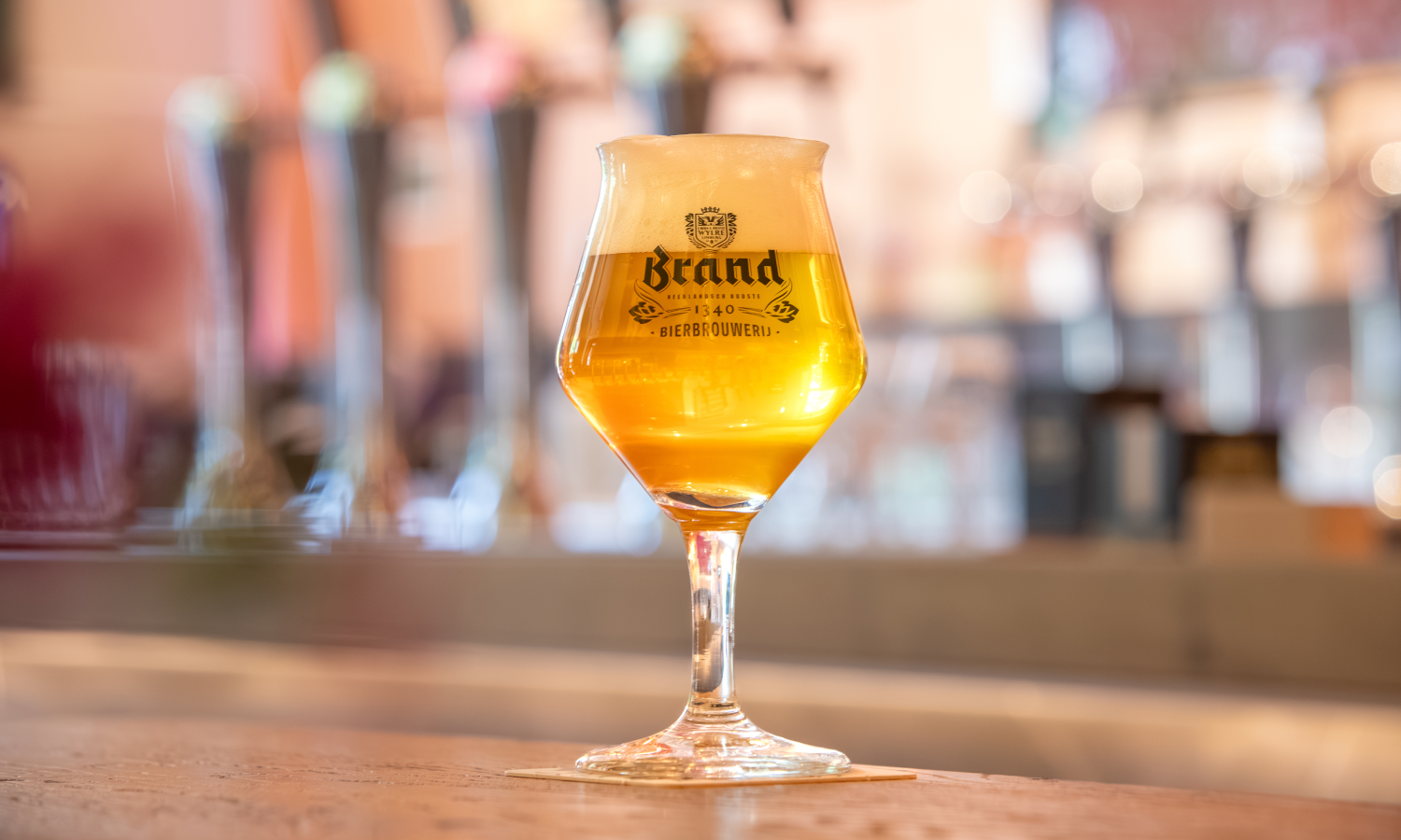 Glas Brand bier met schuimkraag op een bar met wazige achtergrond.