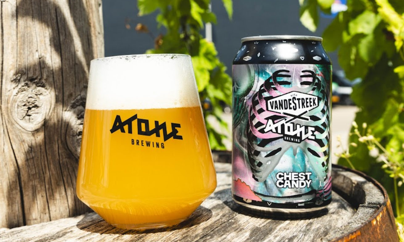 Glas troebel blond bier en blik Chest Candy op een houten vat in zonnige tuin.