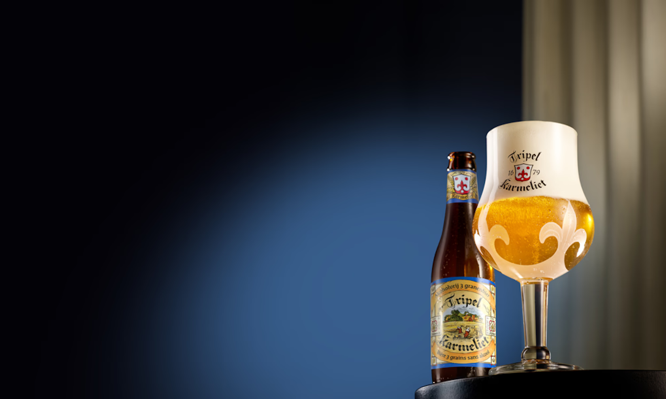 Tripel Karmeliet bierglas en fles op een donkere achtergrond.
