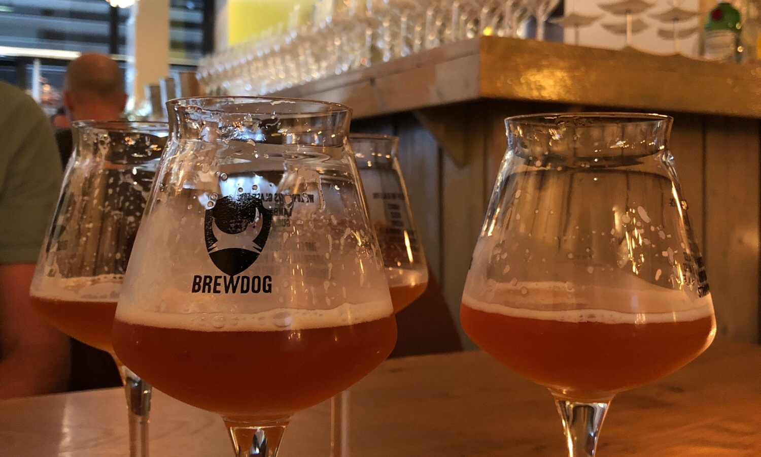 Glazen met BrewDog bier op een houten tafel in een bar setting.