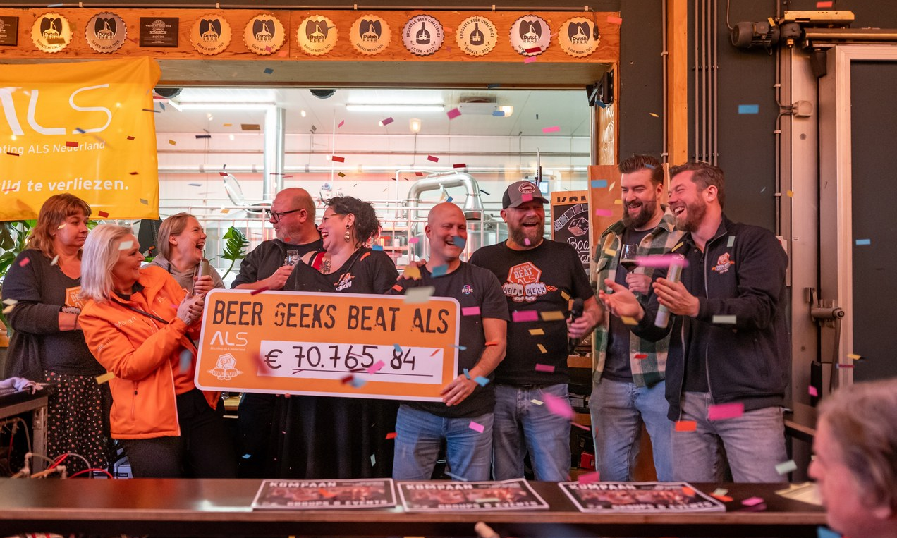 Mensen vieren en houden een cheque omhoog voor Stichting ALS met confetti in de lucht.