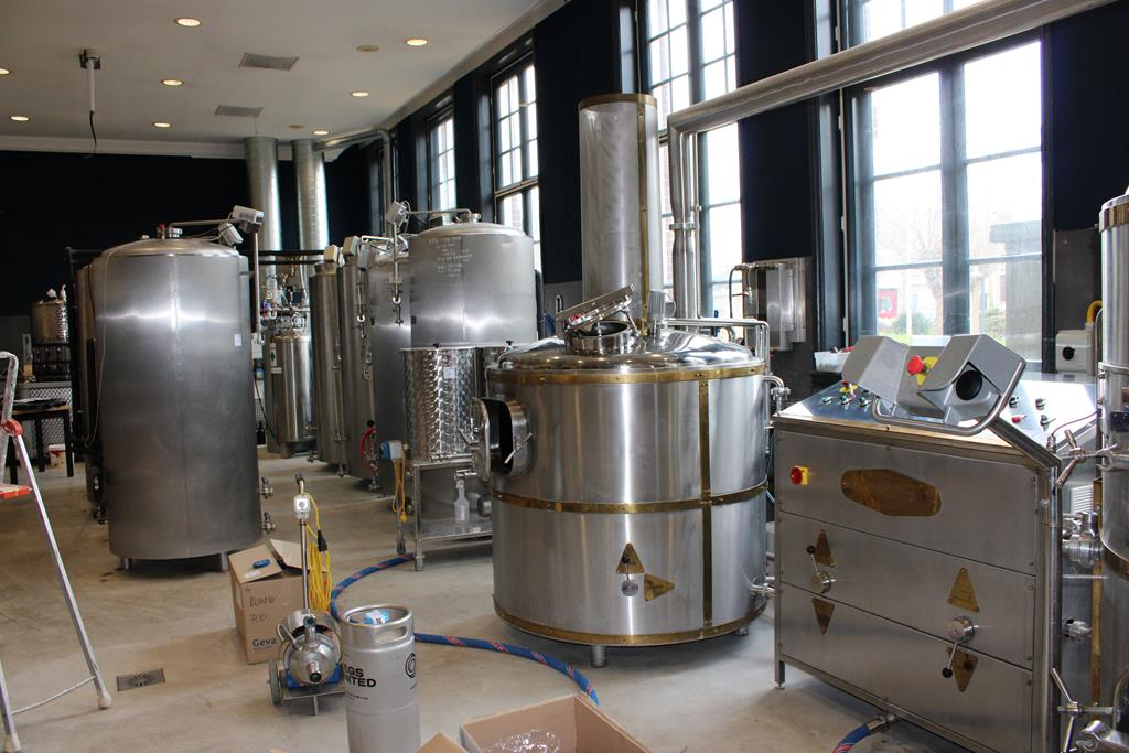 Interieur van een brouwinstallatie met stalen tanks en apparatuur in een verlichte ruimte.