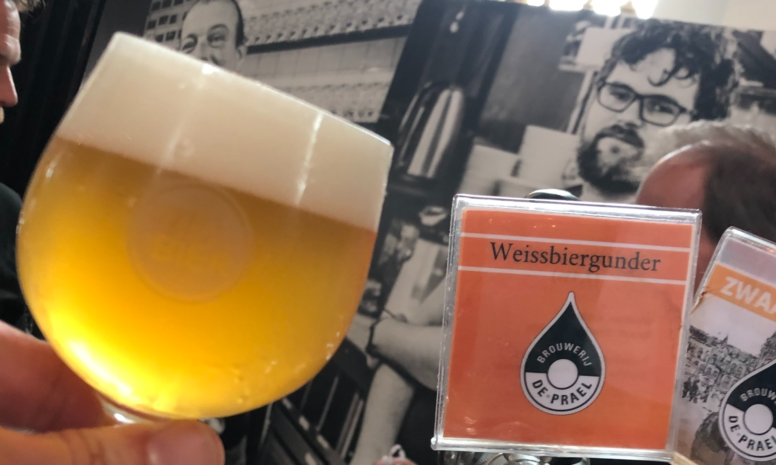 Hand houdt glas bier vast tijdens Week van het Nederlandse Bier evenement.