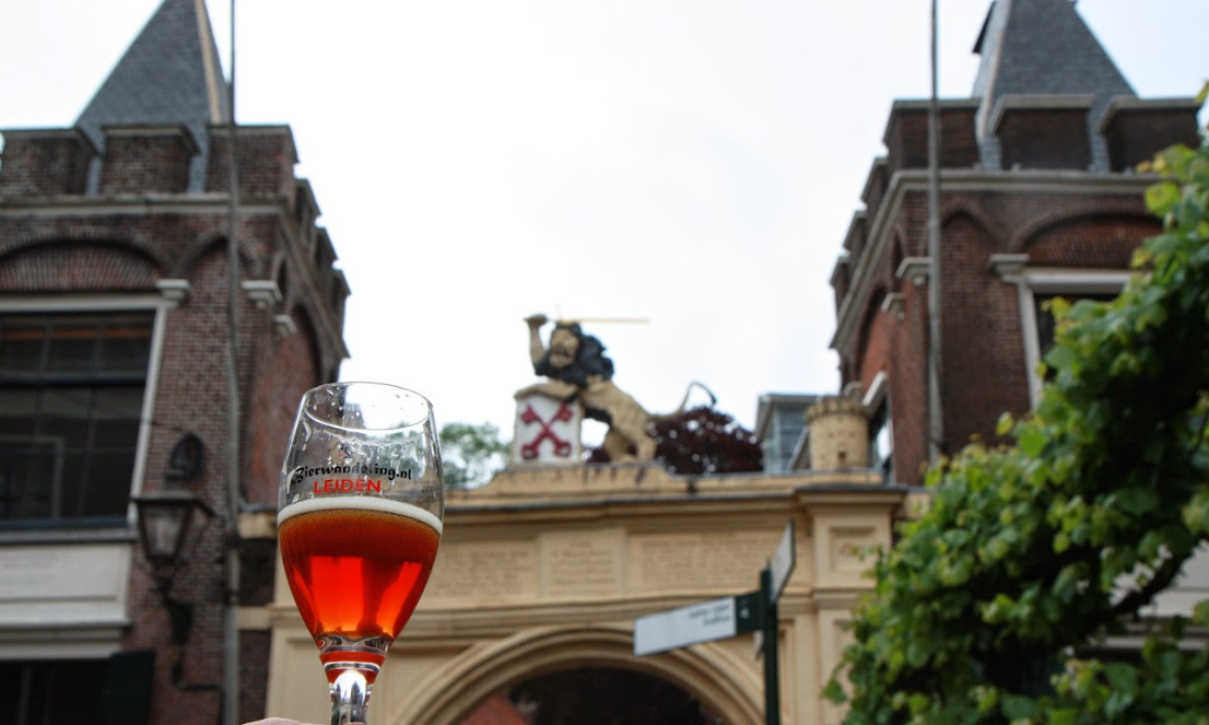 Een glas bier tegen de achtergrond van een historisch gebouw in Leiden.