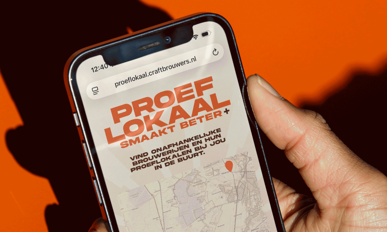 Hand houdt een smartphone vast met de Proef Lokaal website op een oranje achtergrond.