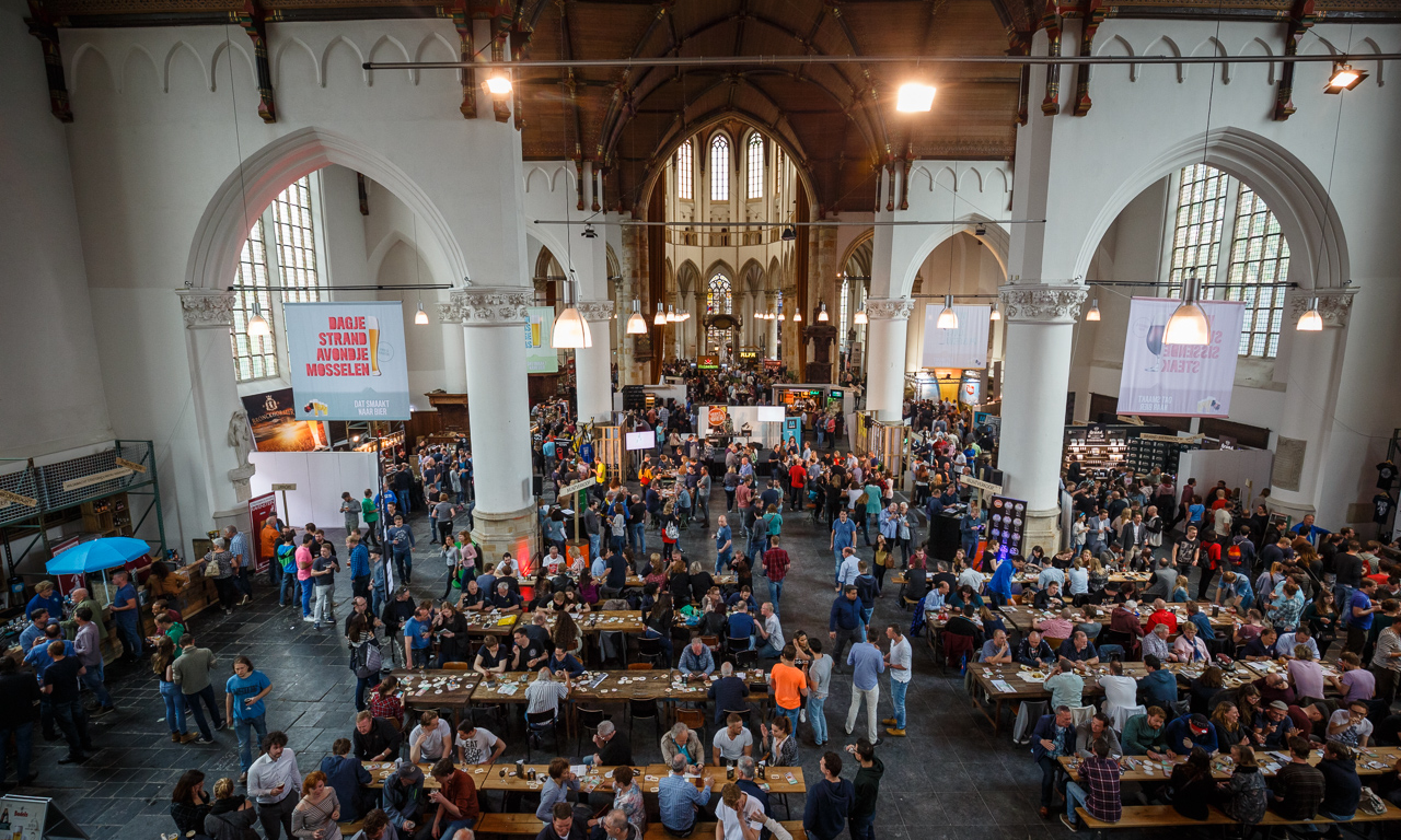 Mensen genieten van het Nederlands Bierproeffestival in de grote kerk in Den Haag