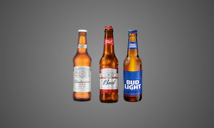 Drie bierflesjes: Budweiser Zero, Budweiser, Bud Light op een grijze achtergrond.
