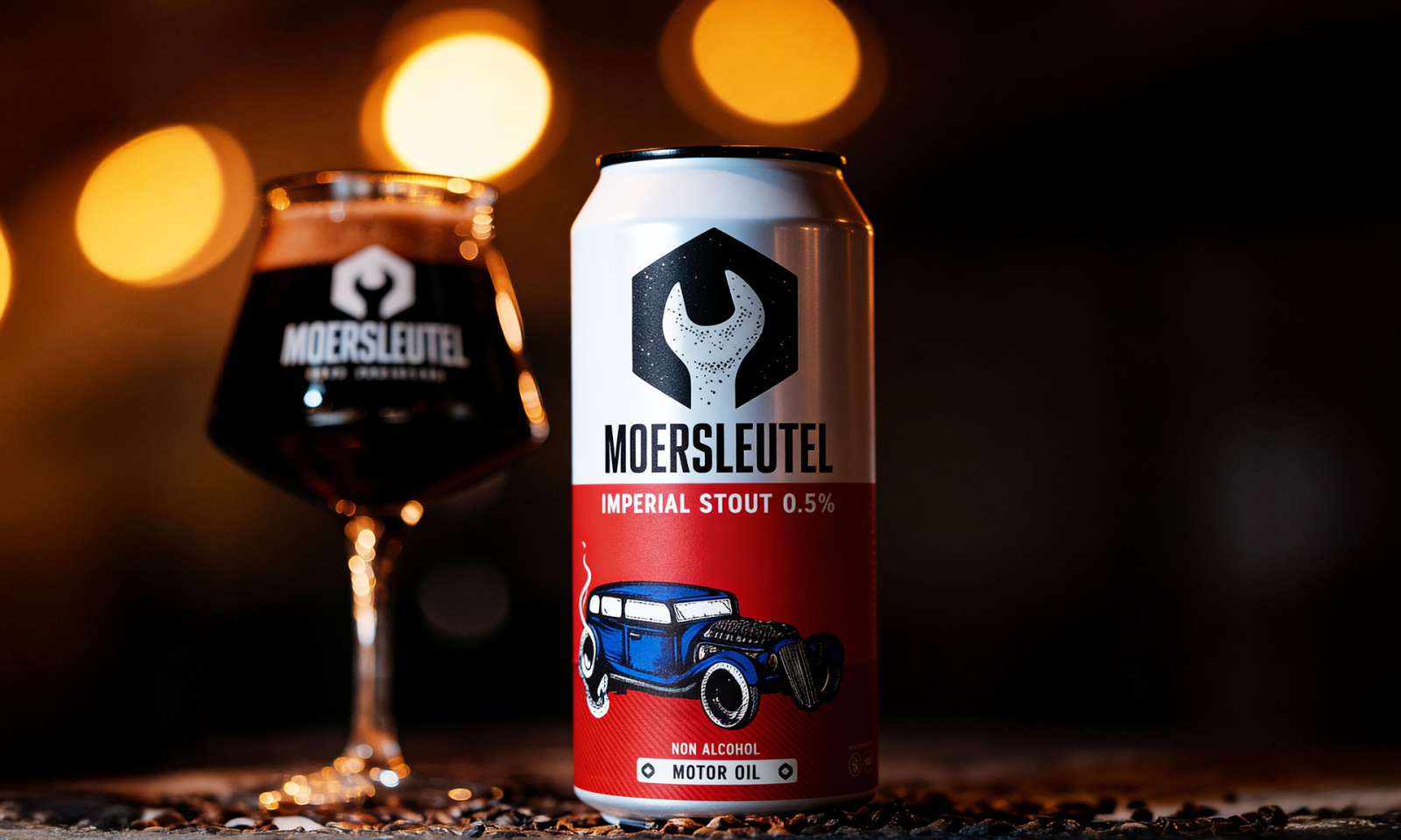 Blik Moersleutel Imperial Stout 0.5% en glas met donker bier op achtergrond.