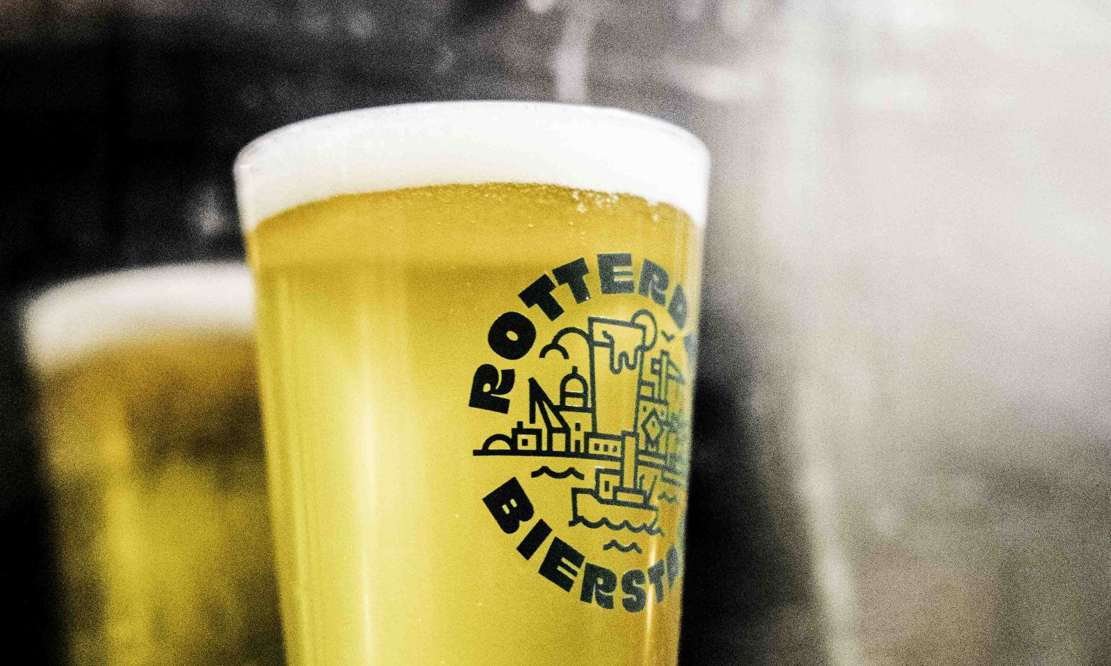 Twee glazen bier met Rotterdamse illustratie en tekst 'Rotterdam Bierstad'.
