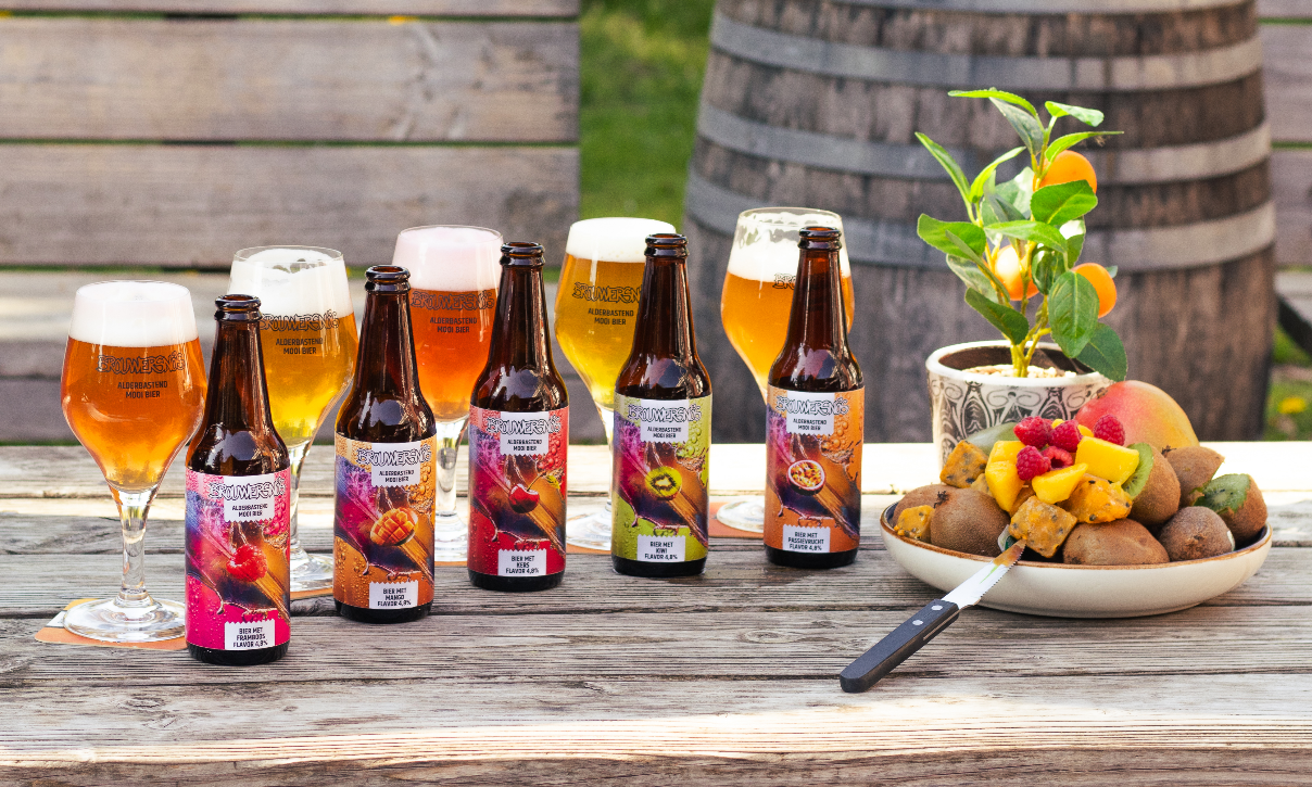 Flessen bier met fruitaroma's en een fruitschaal op een houten tafel buiten.