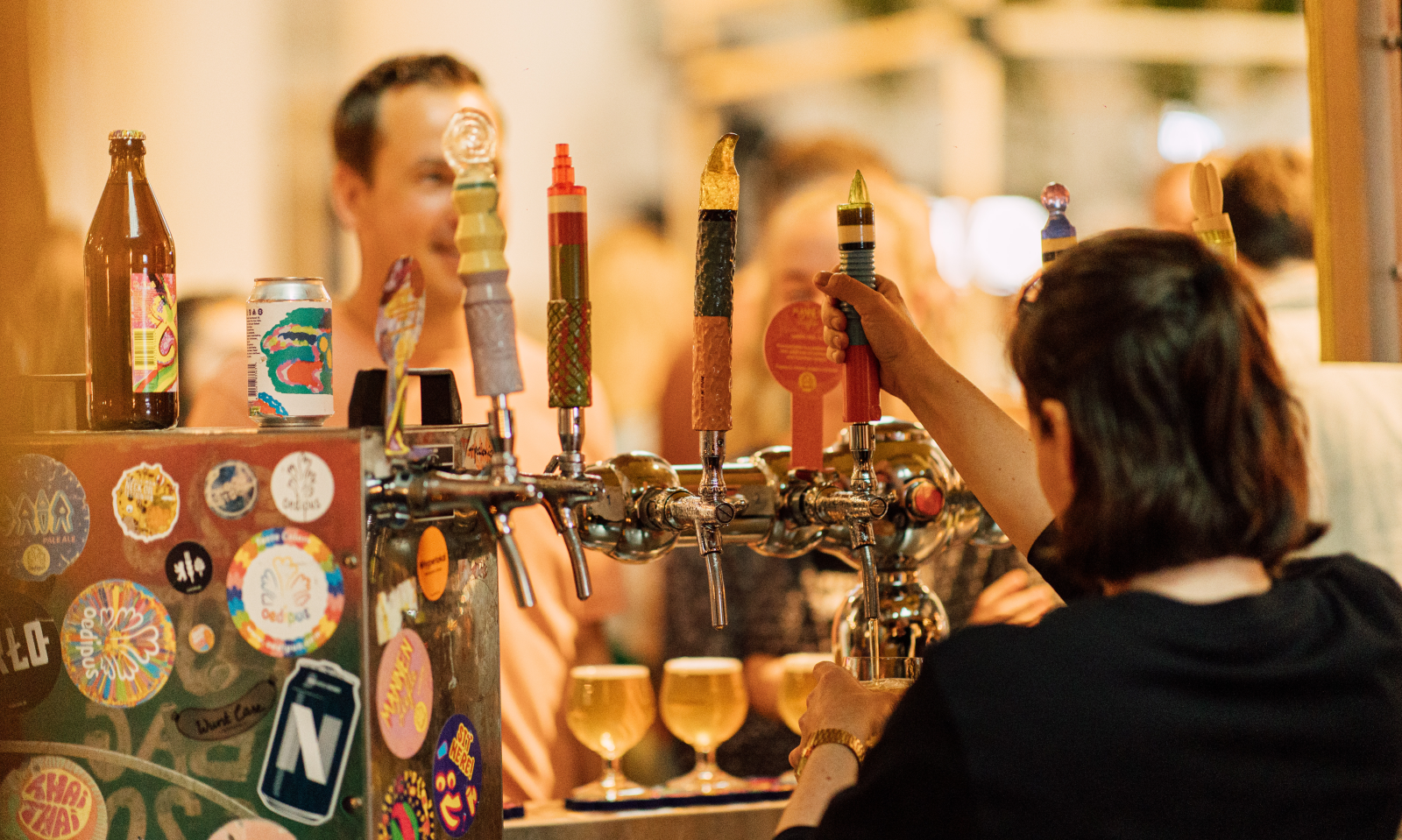 Dame schenkt bier in tijdens een bierfestival met kleurrijke taphendels.