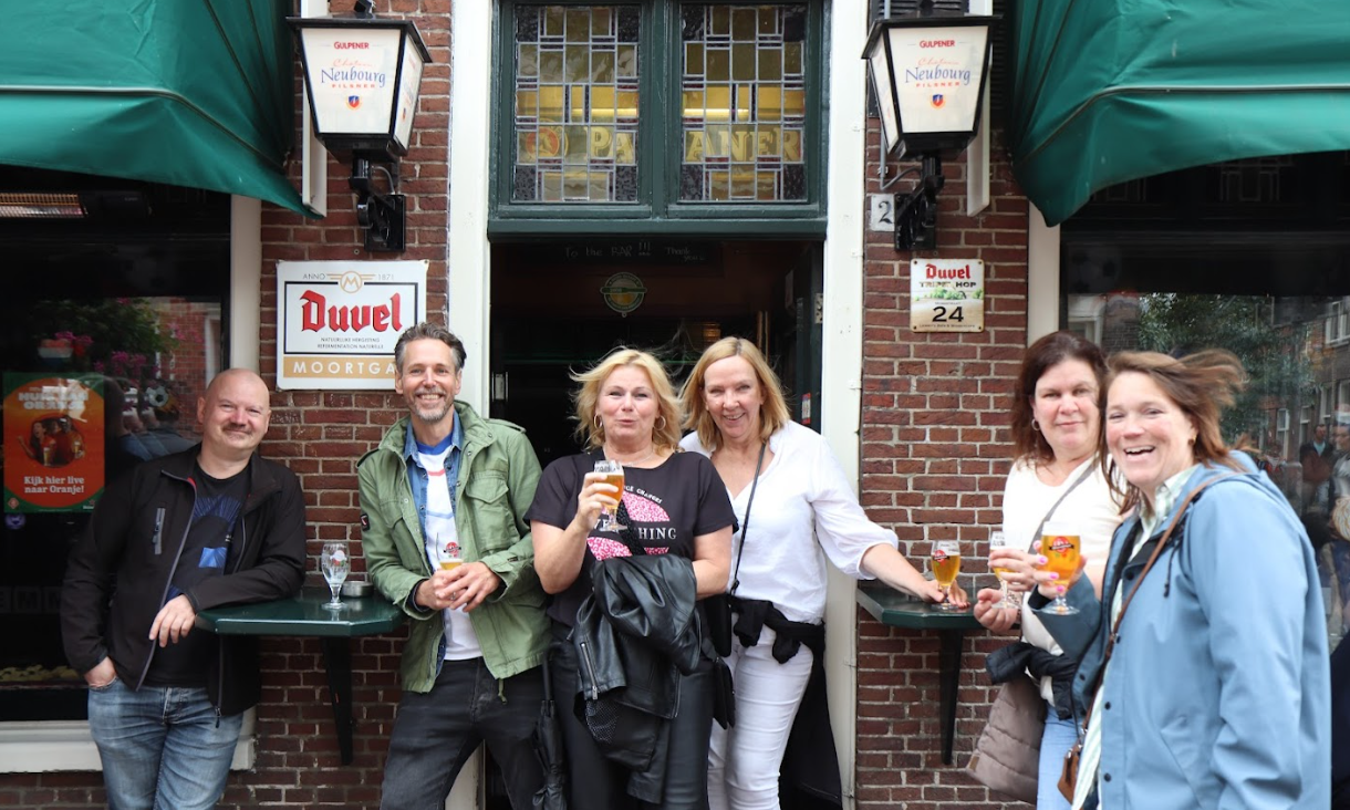 Groep mensen met bier voor een café in Leiden tijdens een bierwandeling.