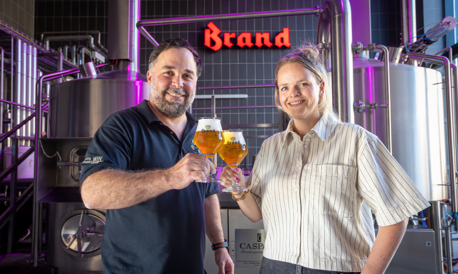 Twee mensen proosten met glazen Brand bier in een brouwerij.