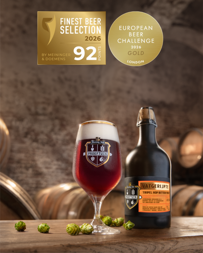 Glas Hertog Jan bier en kruik op houten tafel met gouden keurmerken erboven.