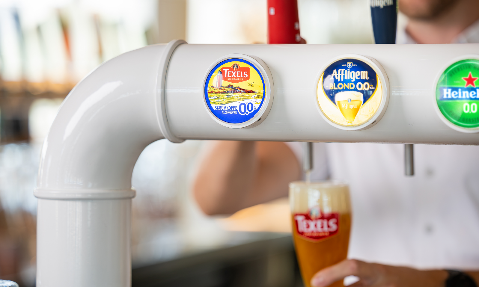 Witte tap met Texels Skuumkoppe 0.0 badge terwijl een glas bier wordt ingeschonken.