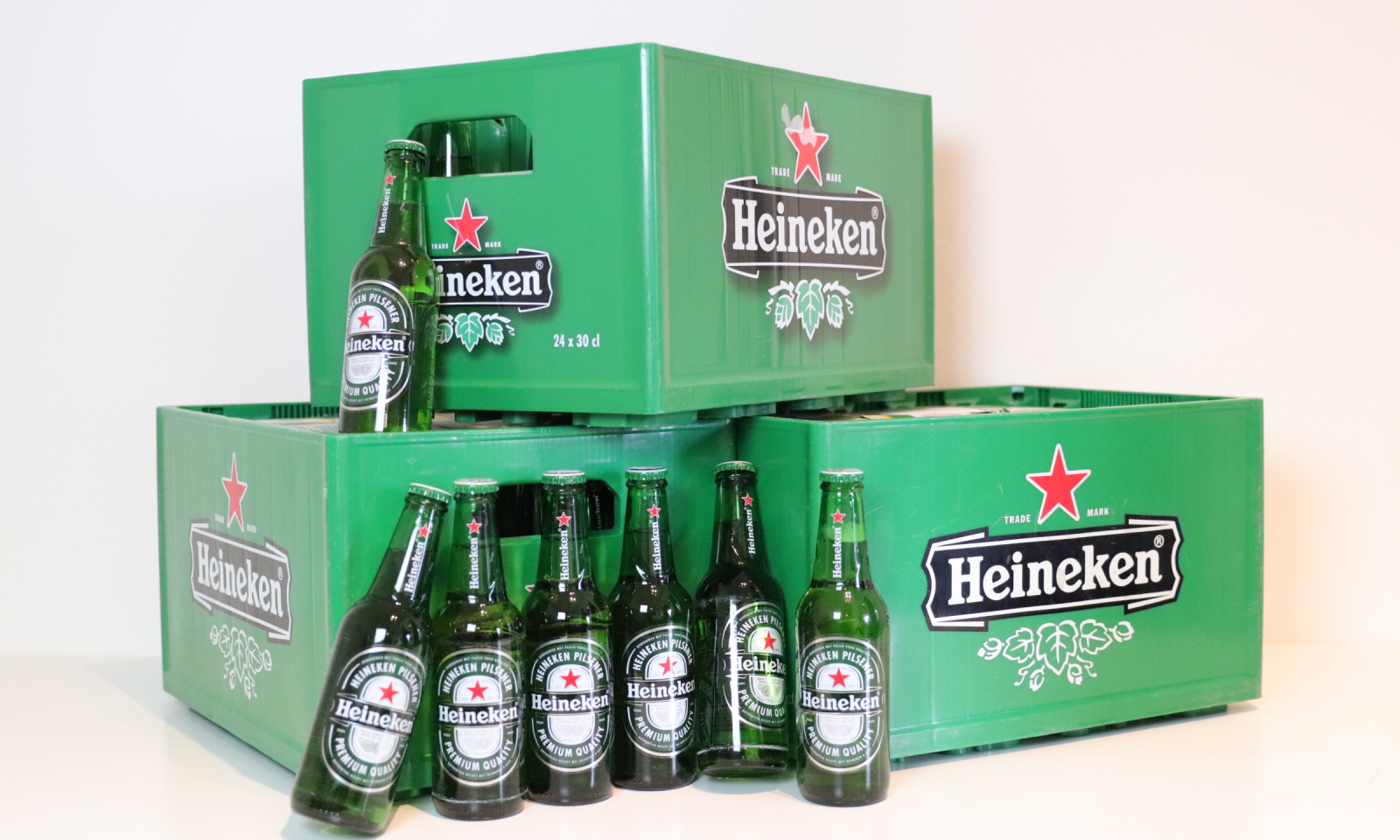 Groene Heineken-kratten met zeven glazen flesjes op een witte achtergrond