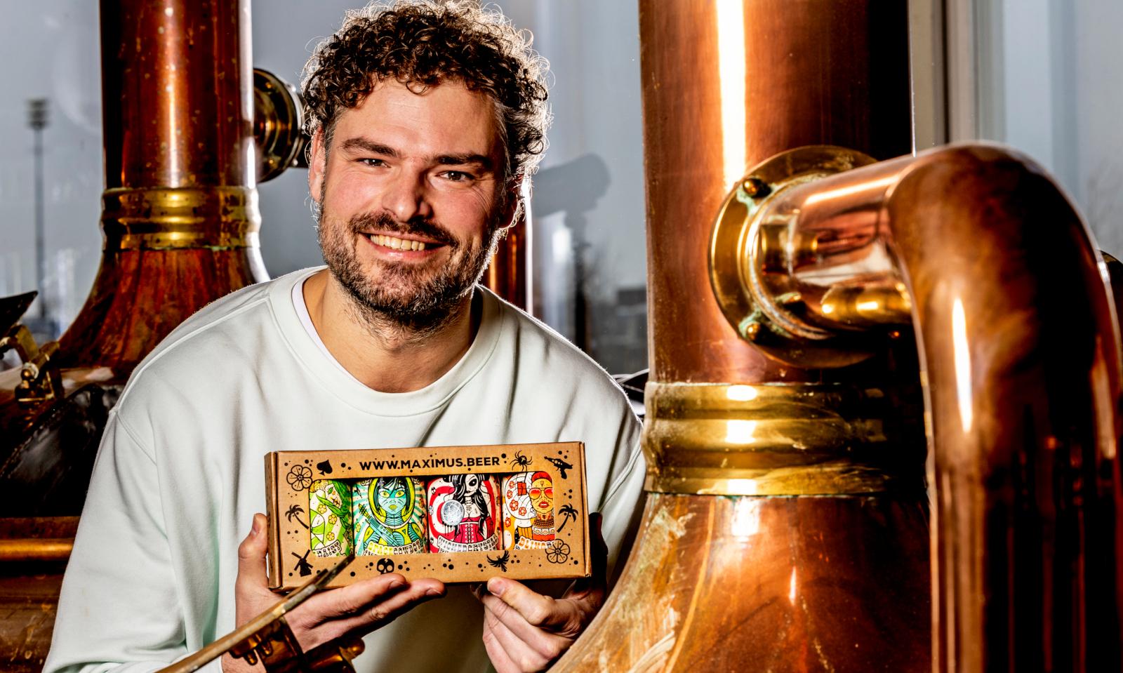 Man toont Maximus cadeauverpakking met bier in blik bij de brouwketel van Brouwerij Maximus