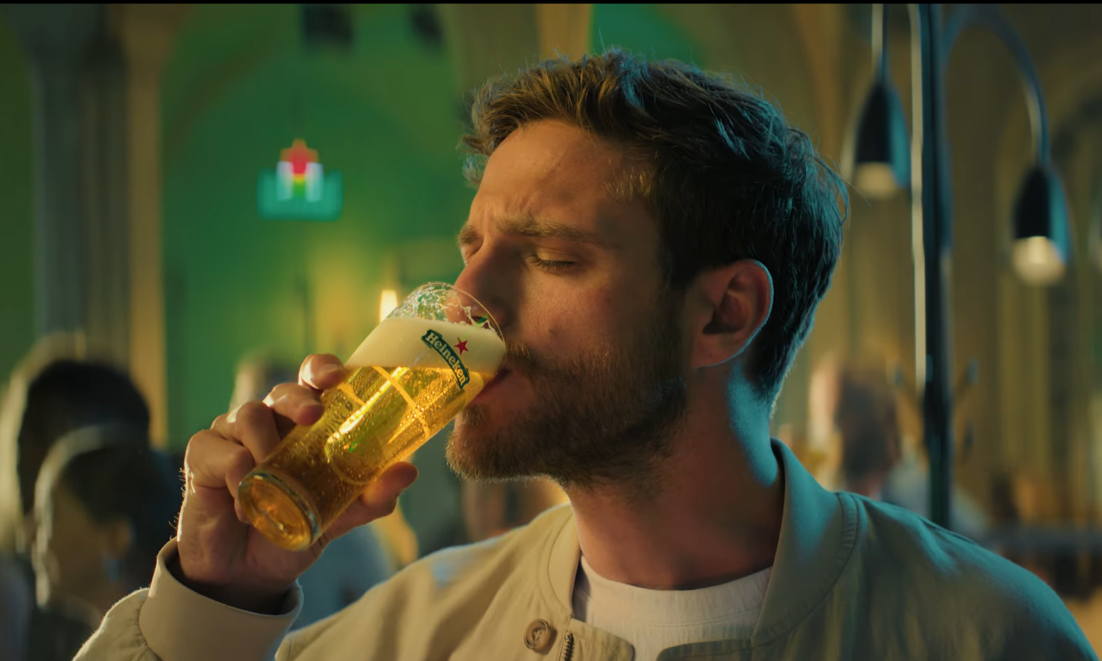 Man drinkt een glas helder bier met een schuimkraag in een sfeervolle bar.
