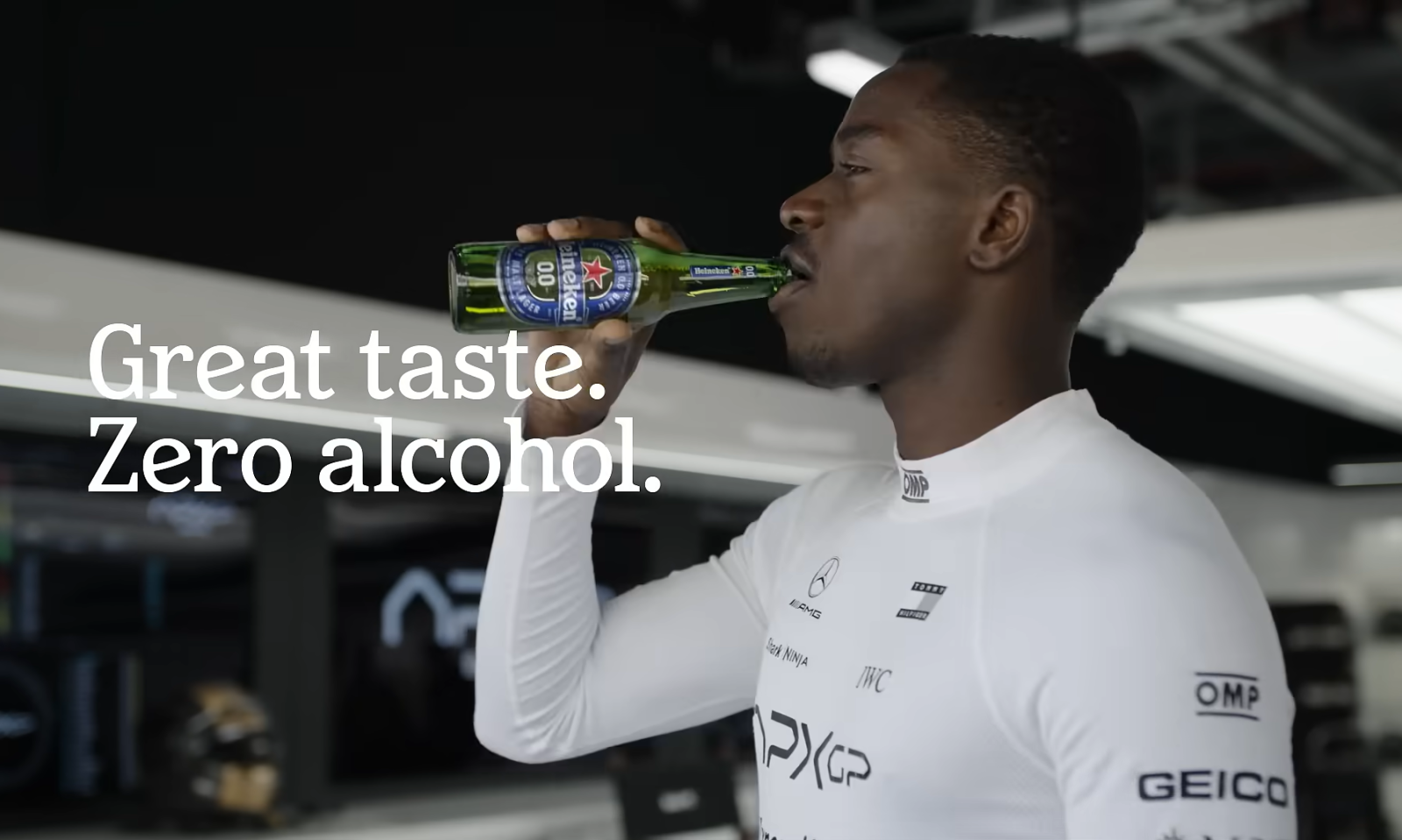 Man drinkt een fles Heineken 0.0 in een raceteam omgeving, tekst: 'Great taste. Zero alcohol.'