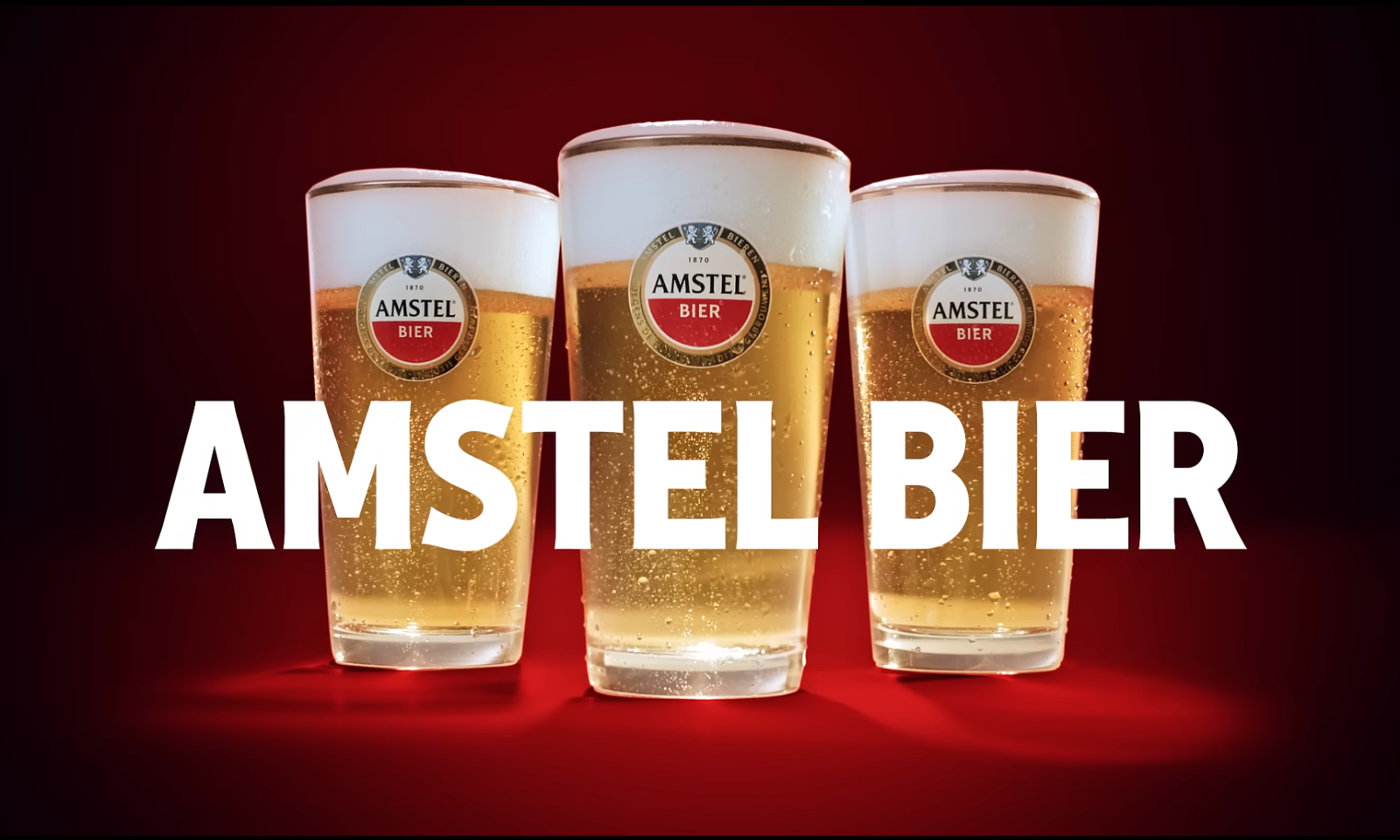Drie glazen Amstel bier op een rode achtergrond met het logo.