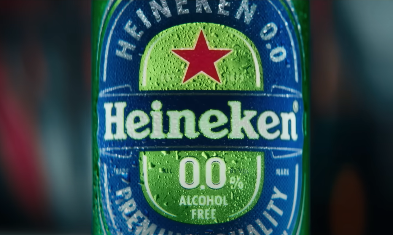 Close-up van een Heineken 0.0 fles met druppels op het etiket, rode ster prominent zichtbaar.