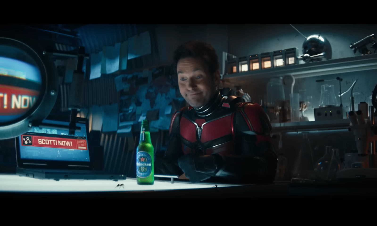 Ant-Man in zijn pak met een fles Heineken 0.0 in een labomgeving.