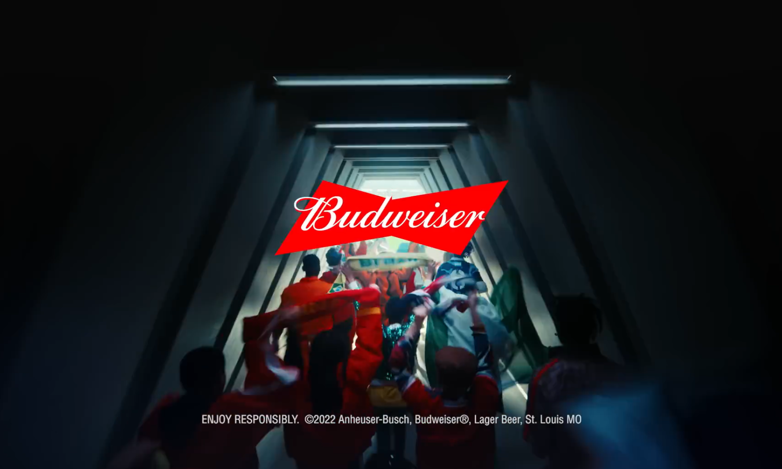 Menigte fans met vlaggen in een donkere doorgang, met Budweiser-logo op de voorgrond.
