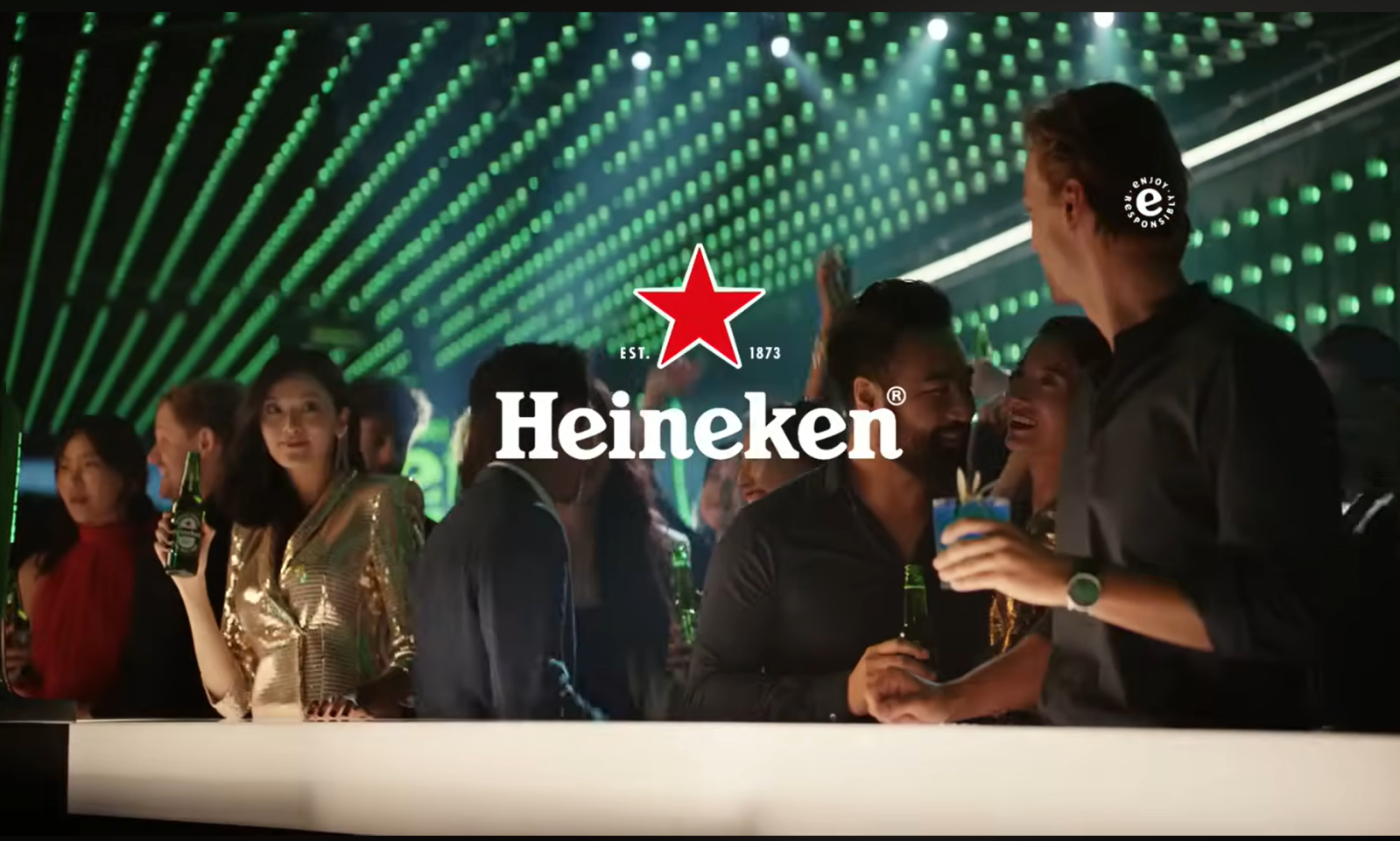 Mensen in een club met een verlichte achtergrond, deels met Heineken flesjes