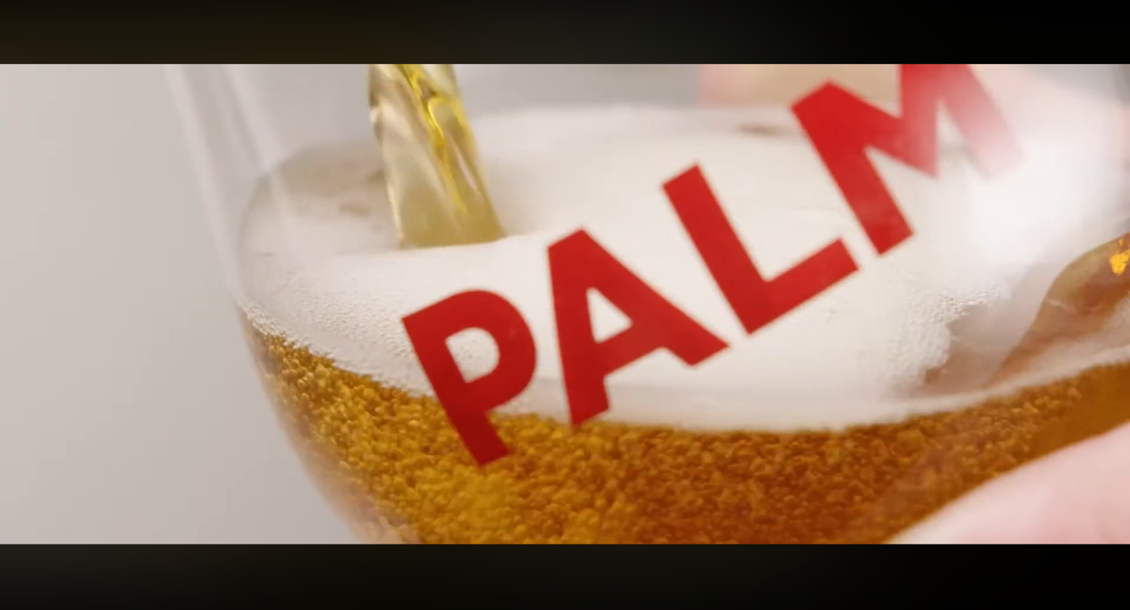 Gouden bier dat in een glas met het rode logo PALM wordt geschonken.