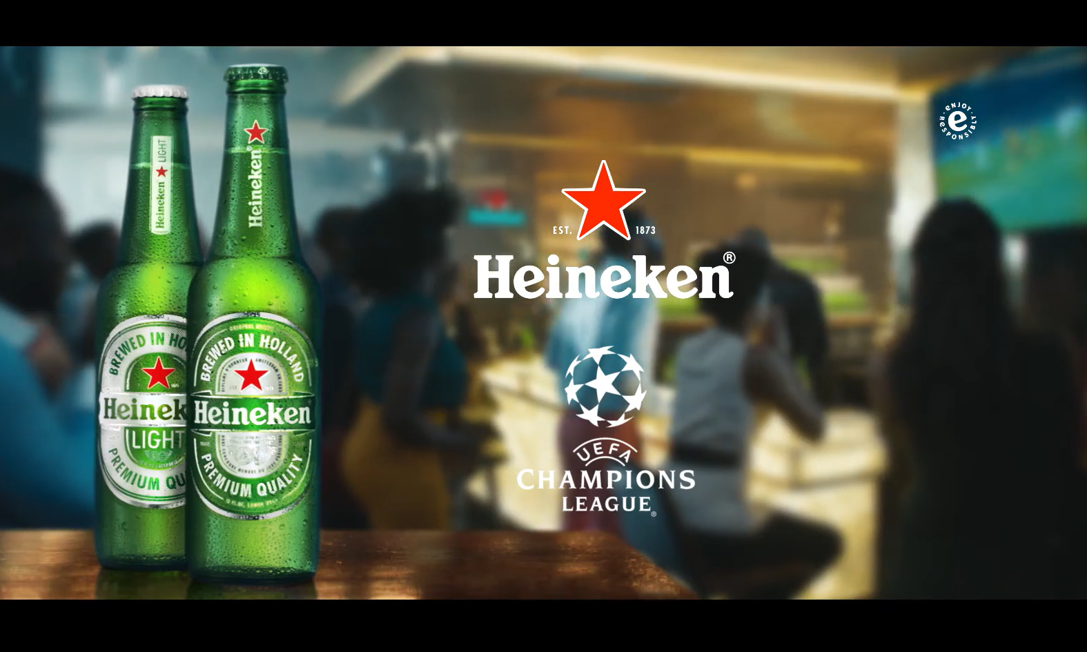 Twee Heineken bierflessen voor een bar met mensen die een UEFA Champions League wedstrijd kijken.