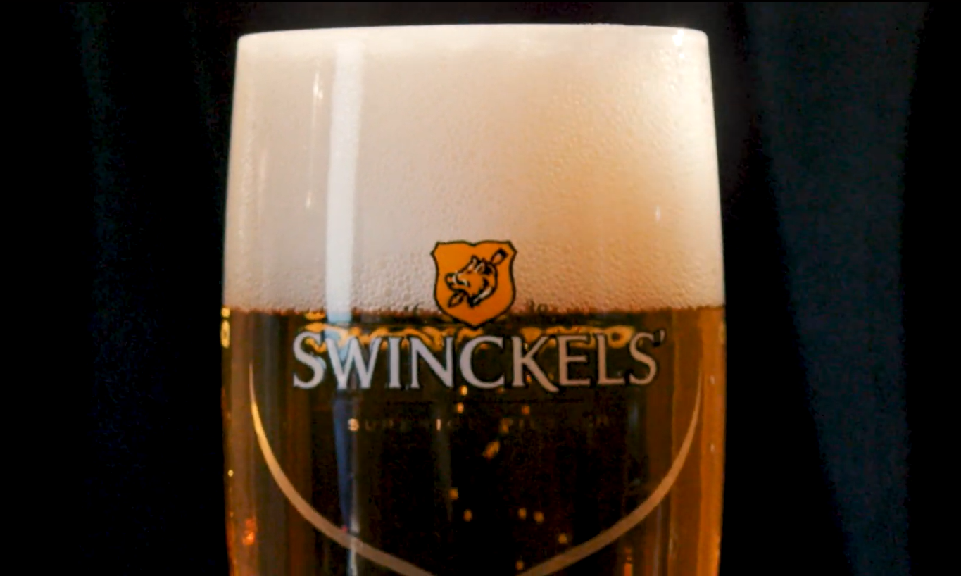 Een glas met schuimend bier van het merk Swinckels