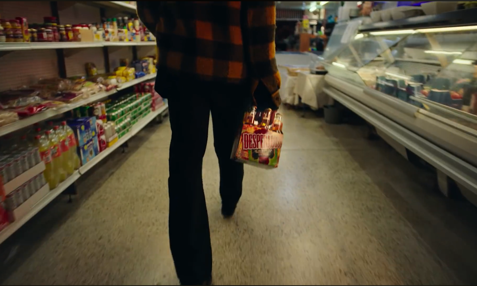 Persoon wandelt door supermarkt met een sixpack Desperados.