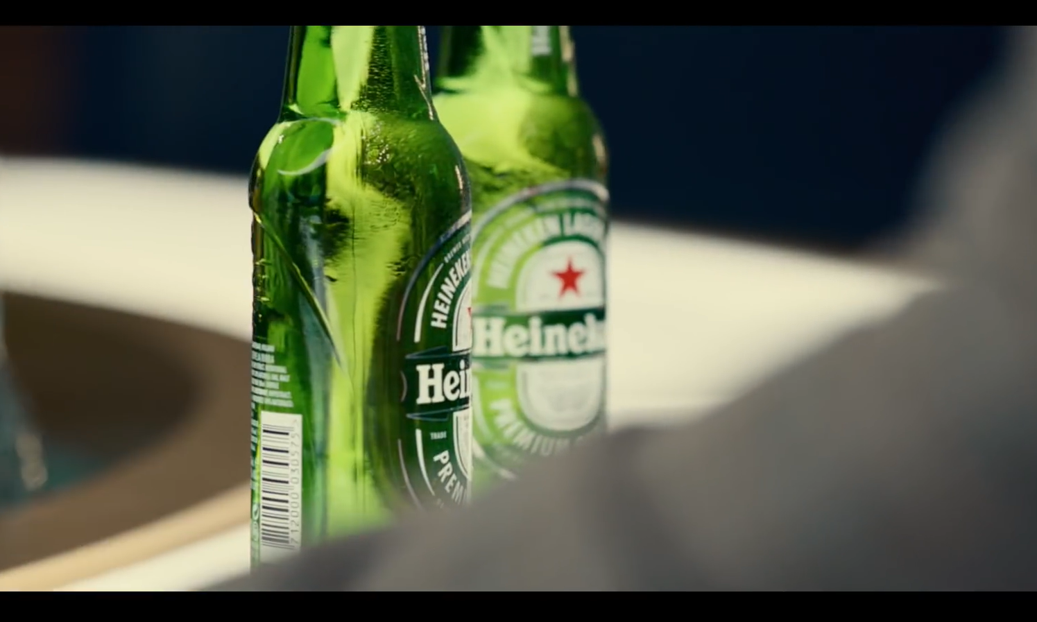Twee groene Heineken bierflessen staan op een tafel bij een plateau.