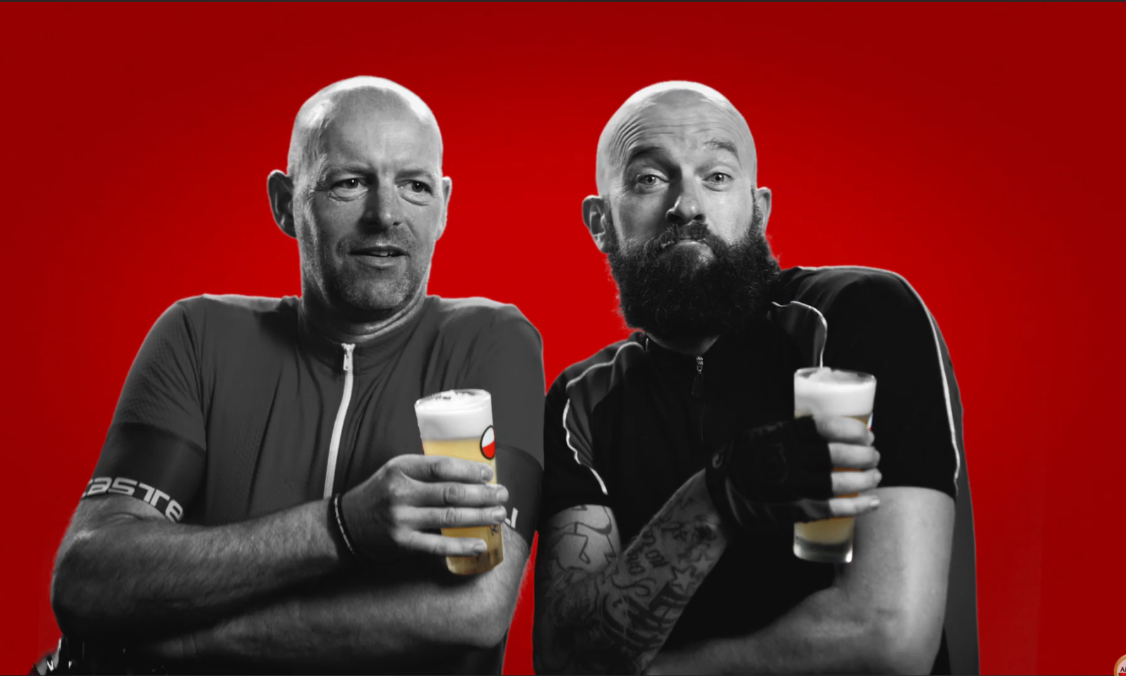 Twee mannen in zwart-wit met glazen Amstel Radler tegen een rode achtergrond.