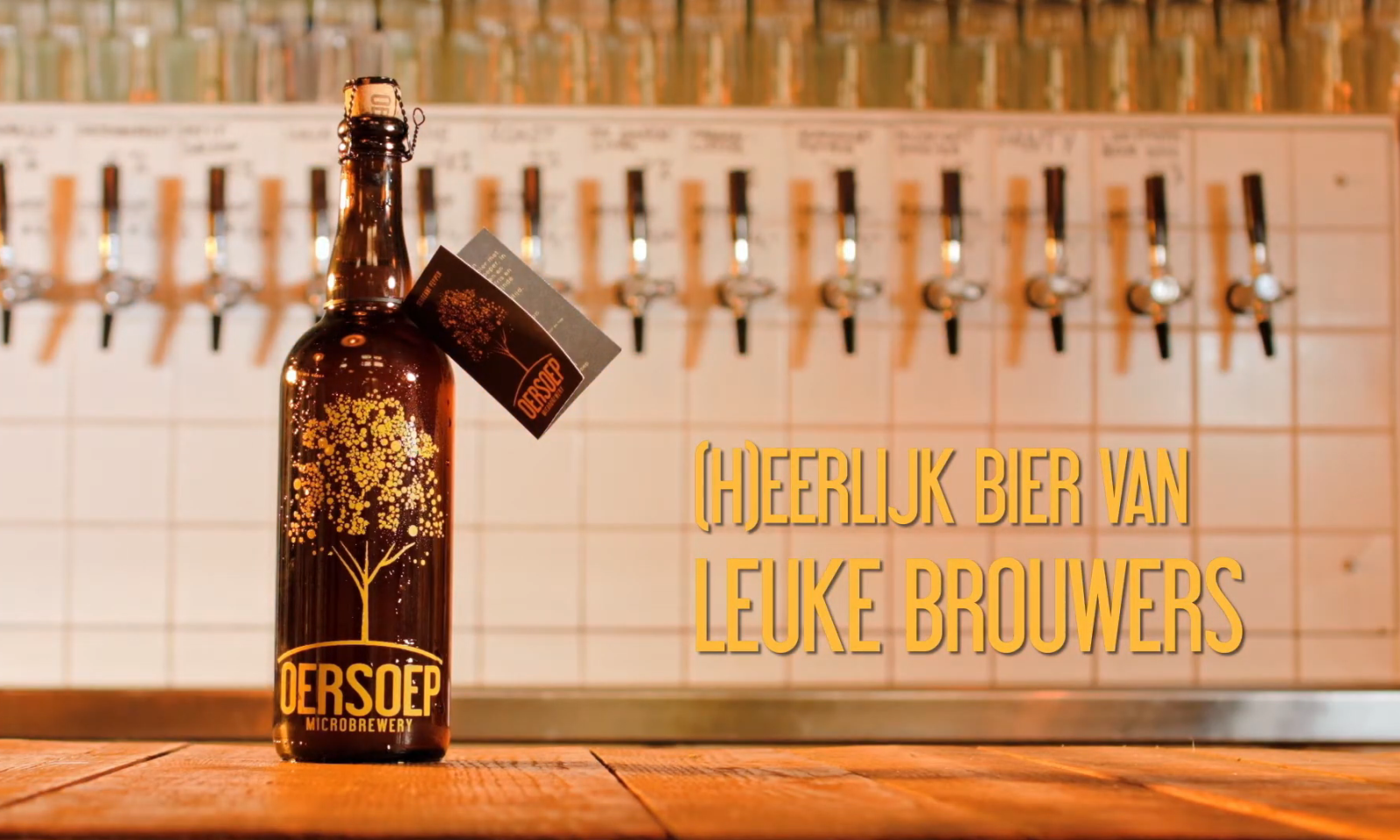 Een fles Oersoep bier voor een rij biertaps met gele tekst 