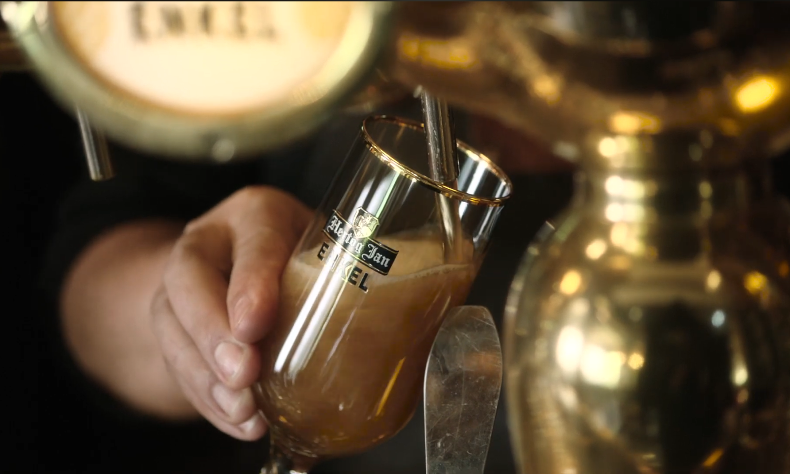 Close-up van een hand die een glas Hertog Jan Enkel tapt vanuit een bierkraan.