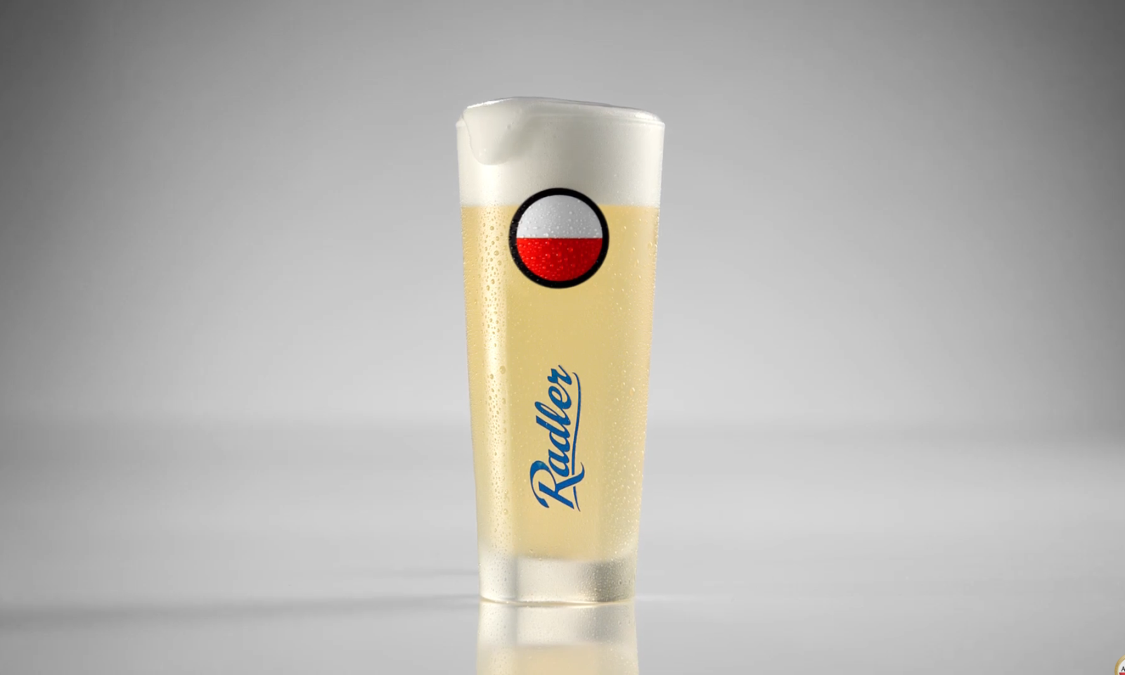 Een glas met Amstel Radler Fris 0.0 bier op een grijze achtergrond.