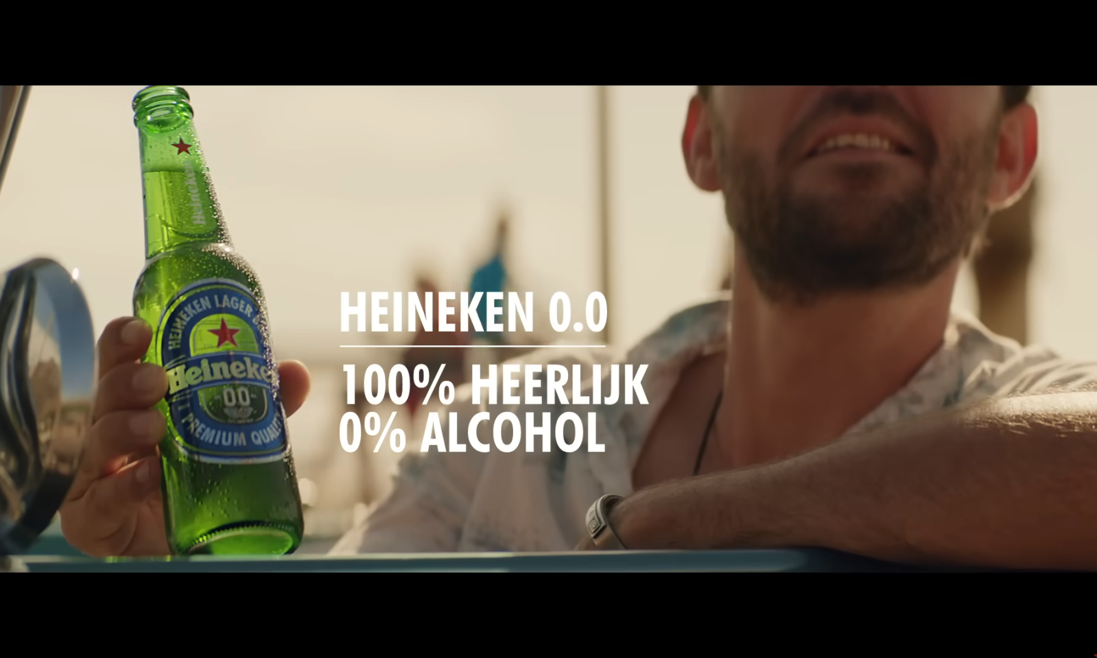 Man in auto houdt een fles Heineken 0.0 vast met tekst 