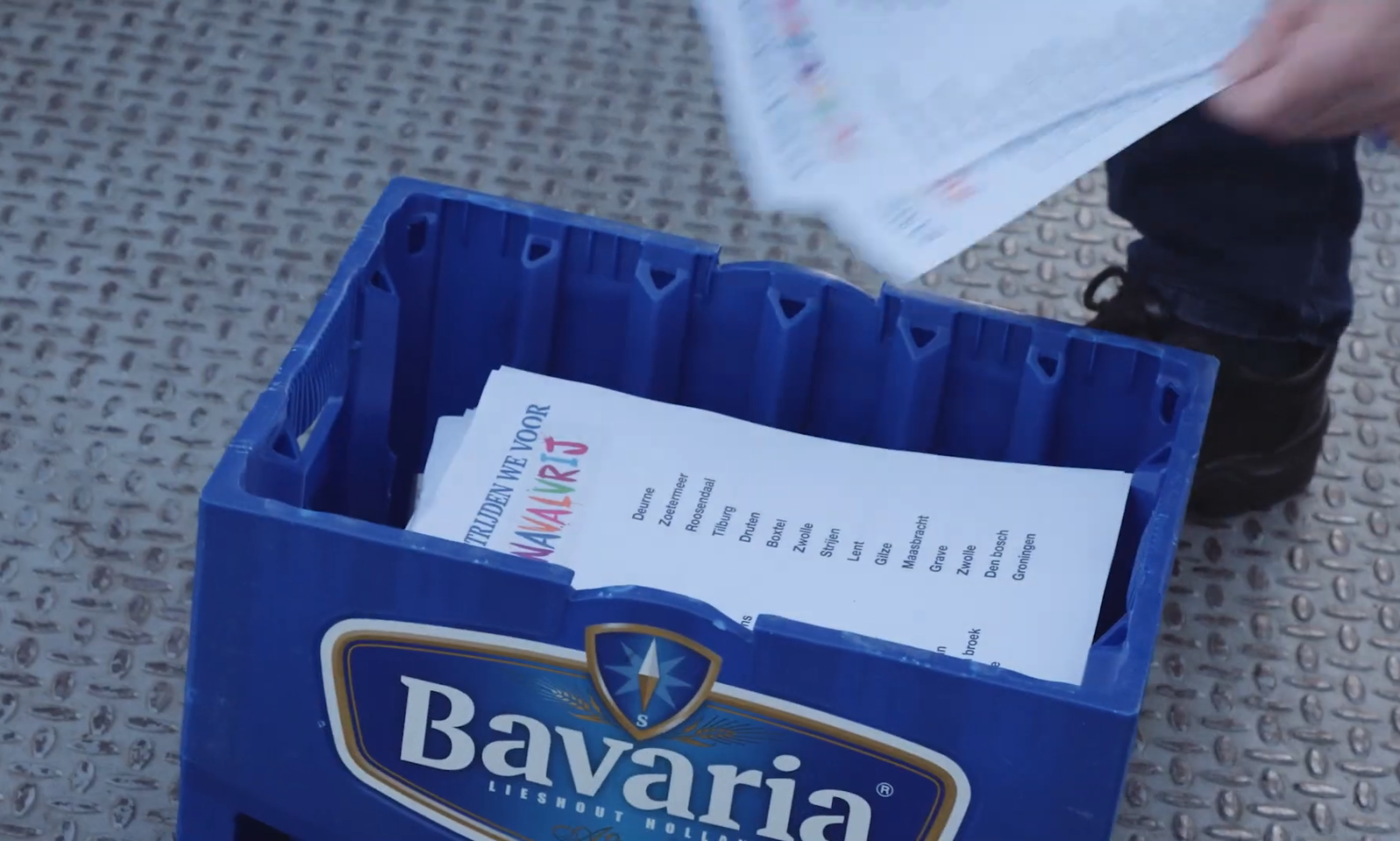 Blauwe krat met papieren op een metalen vloer.