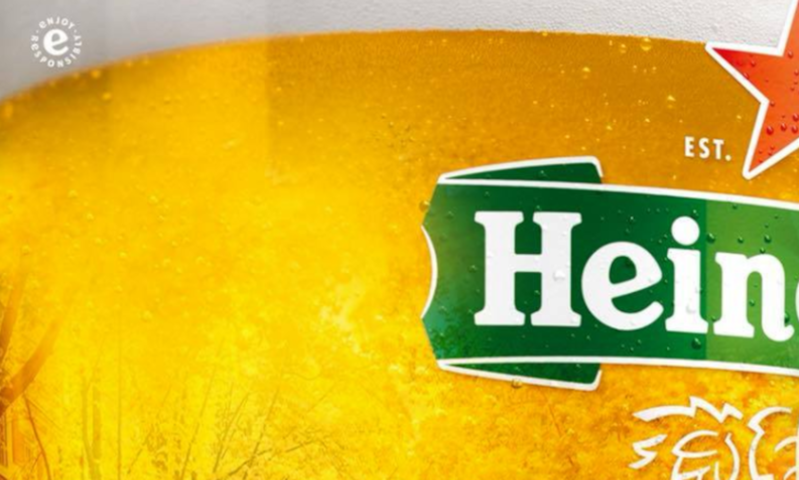 Gedeeltelijke close-up van een Heineken bierglas met gele achtergrond.