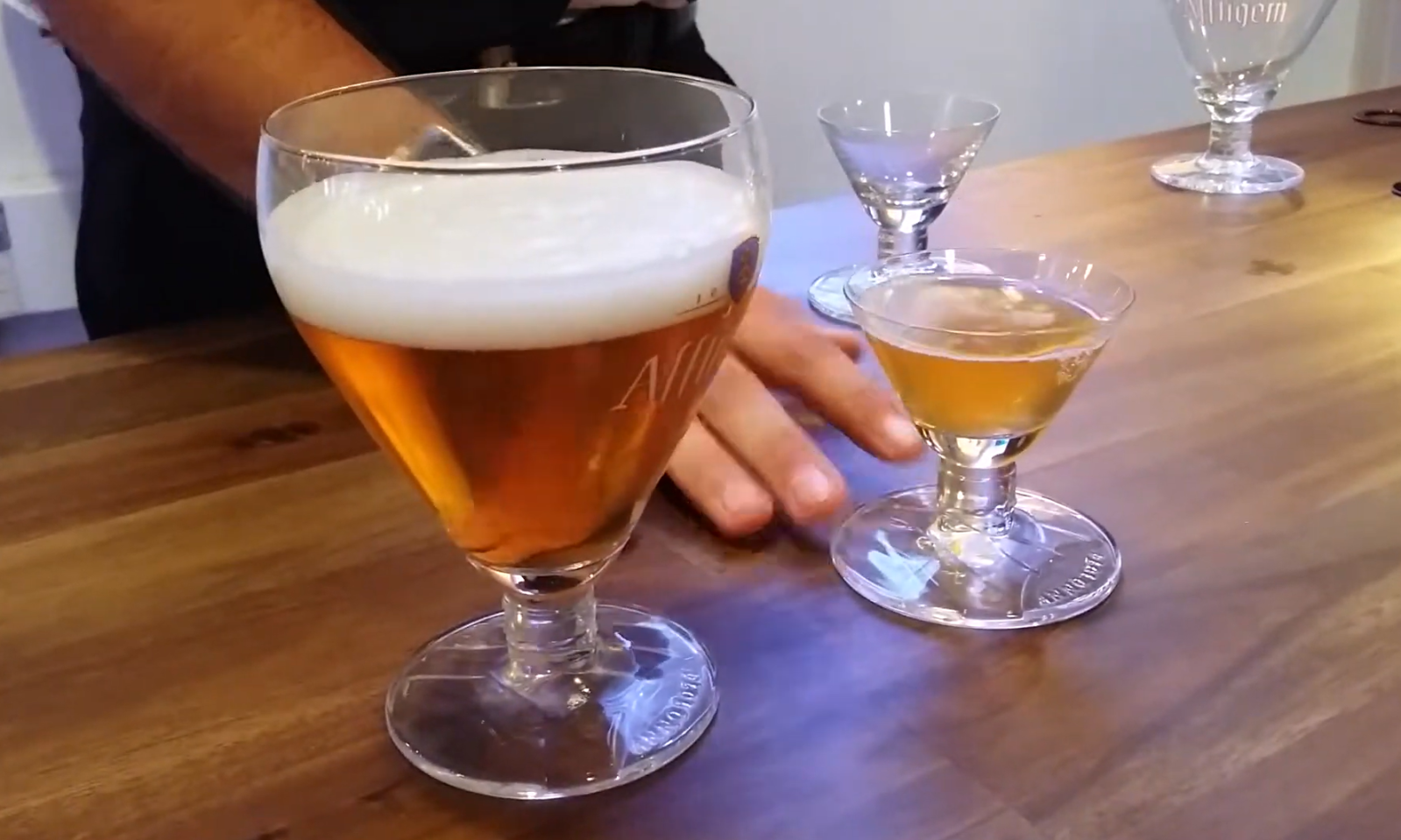 Twee glazen met Affligem bier op een houten tafel tijdens het schenkritueel.