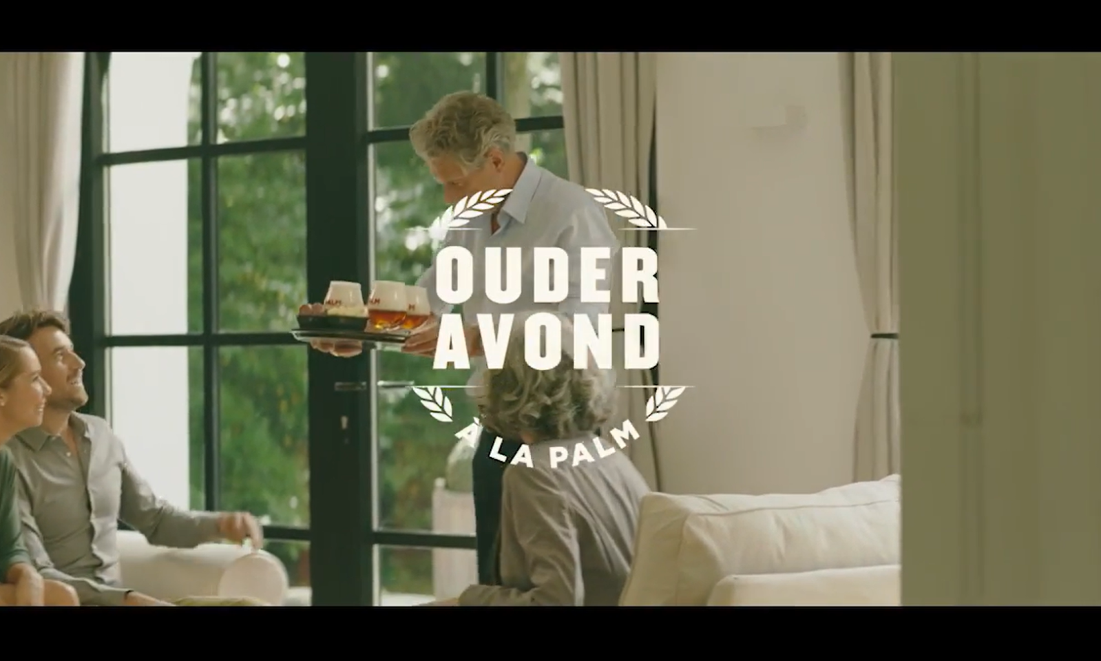 Mensen in een woonkamer met een man die drankjes serveert.