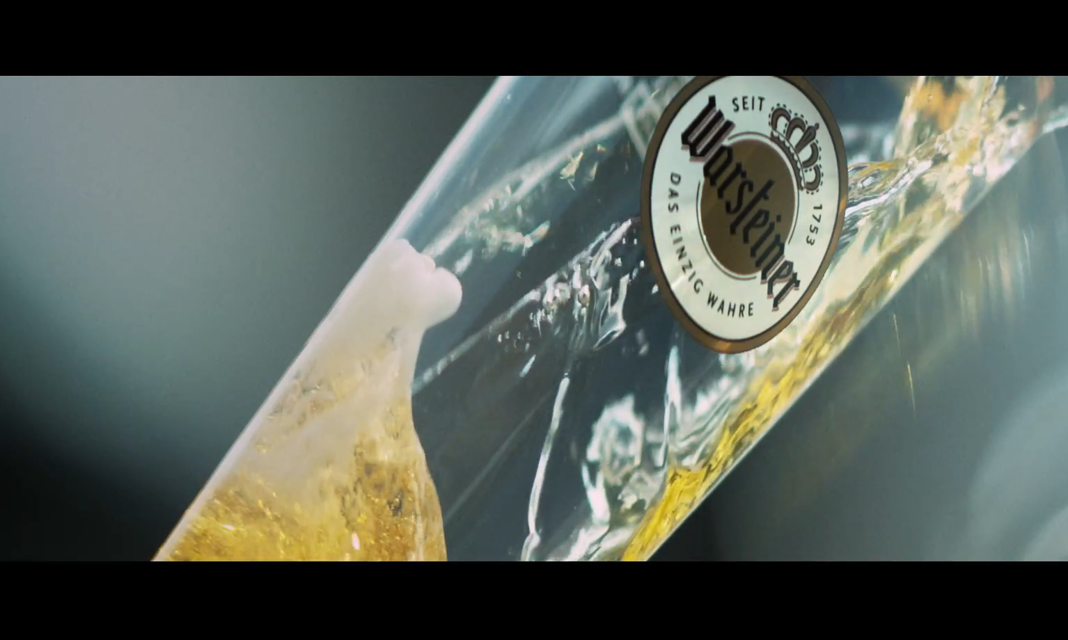 Glas Warsteiner bier wordt ingeschonken, branding zichtbaar.